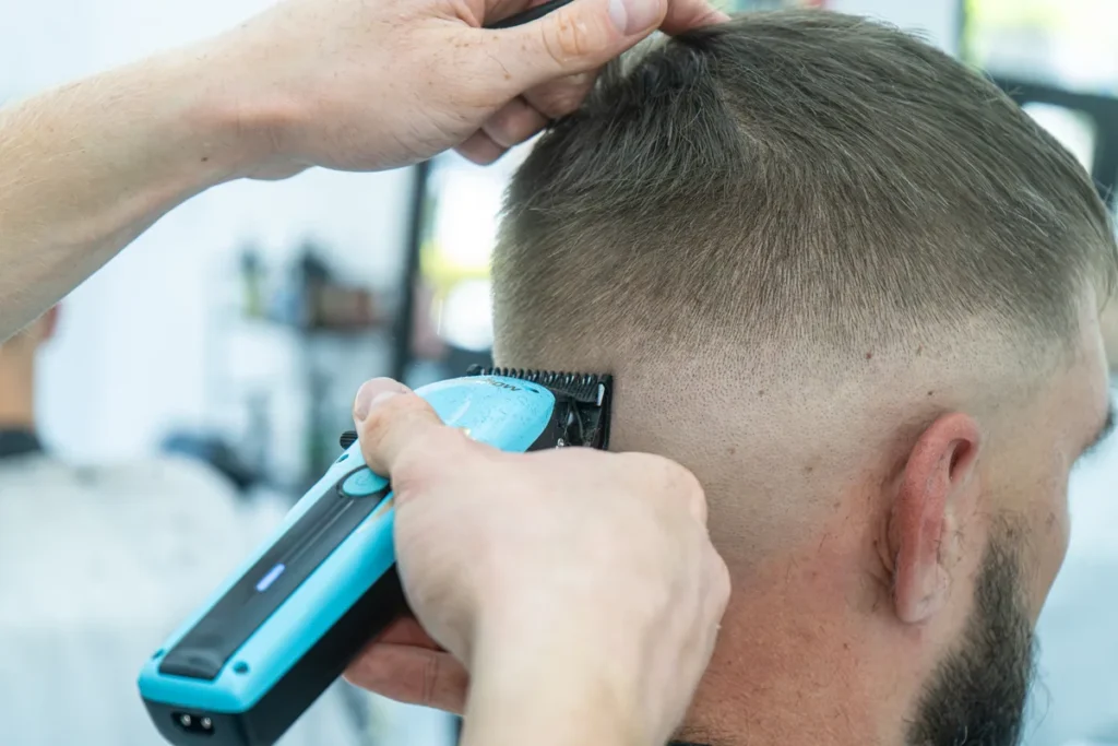 Barber wykonuje cieniowanie włosów przy skroni za pomocą trymera