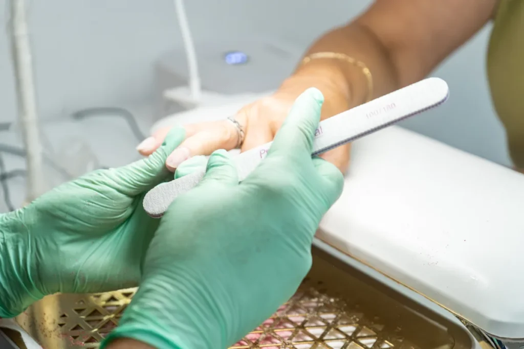 Zbliżenie na pilnikowanie pojedynczego paznokcia podczas zabiegu manicure